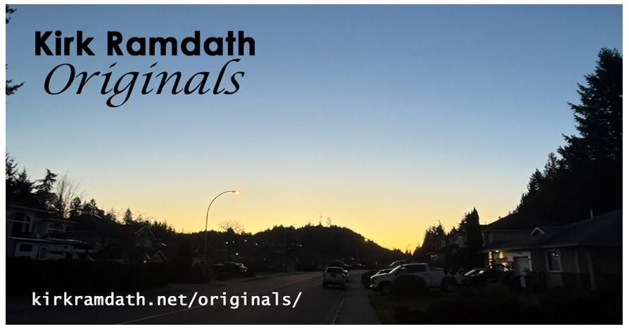 Image shows the line of a neighbourhood and hill in darkness; the sun rising behind makes a sharp yellow line over the hill.